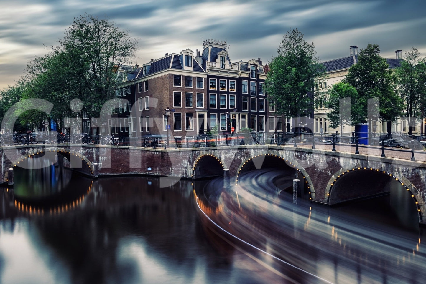 Amsterdam Canal Dreams wallpaper mural shown as a full-wall view of lit canal bridges and Dutch houses at dusk