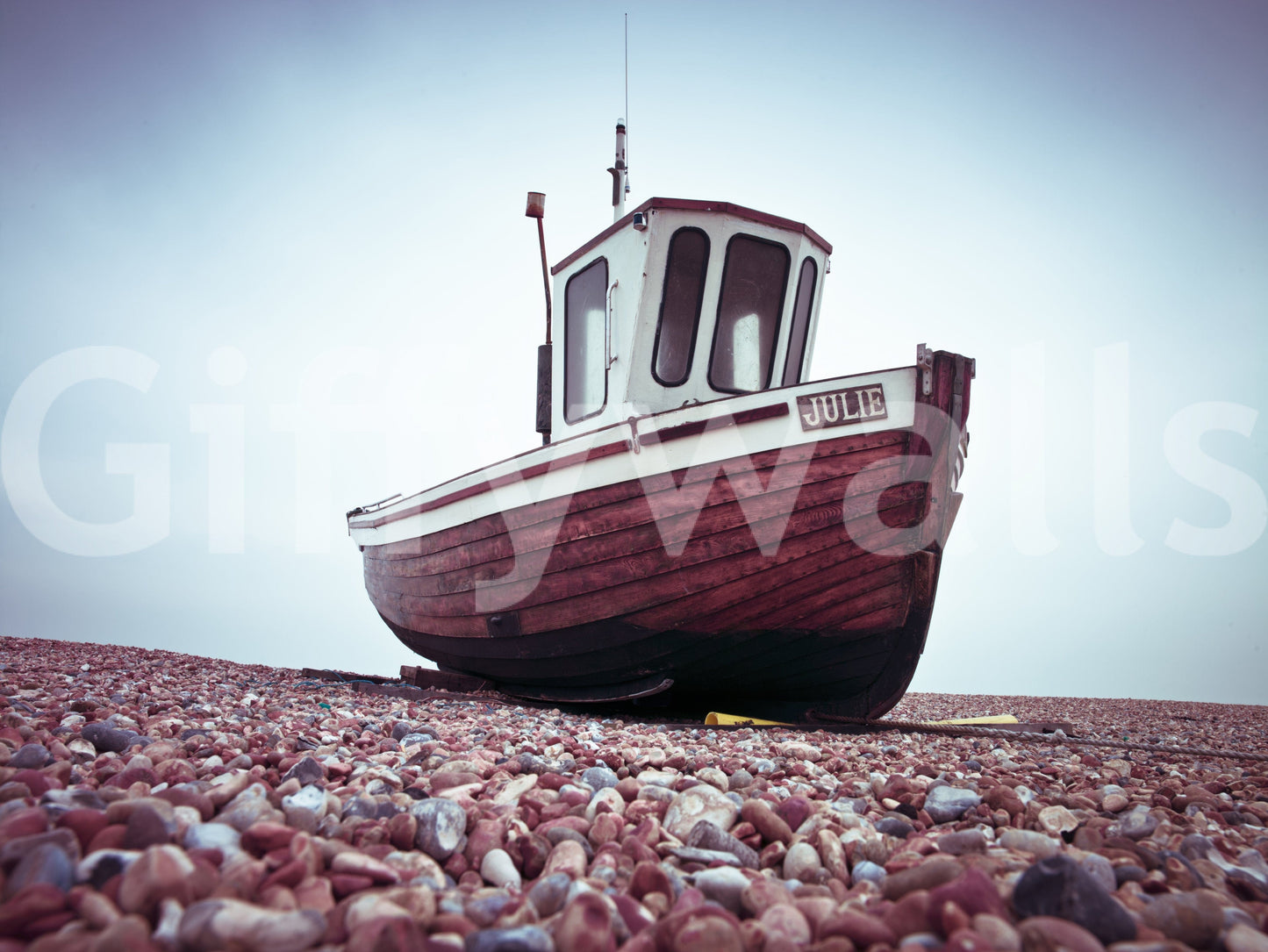 Boat Resting on Pebbled Strand, dark wooden vessel, rocky ground, wall covering.