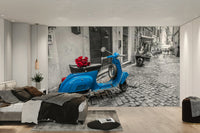 A wall mural of a blue scooter on a cobblestone street.

