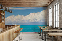 A clear blue sky is visible above a long row of white clouds.

