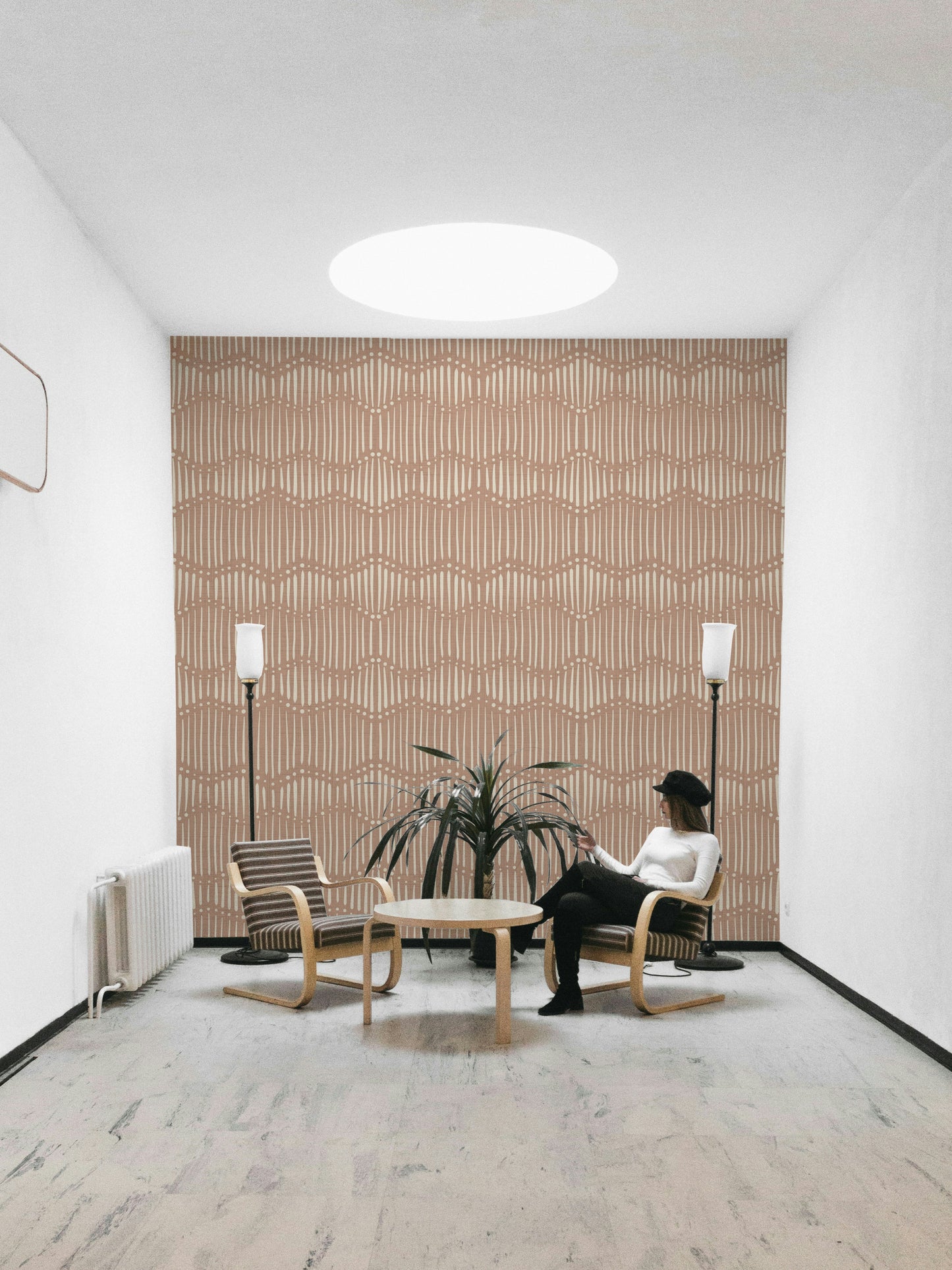 The mural is installed in a calm, bohemian living room behind a simple, light-colored sofa.

