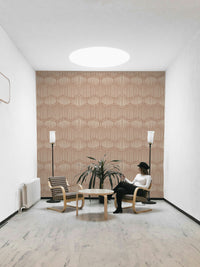 The mural is installed in a calm, bohemian living room behind a simple, light-colored sofa.

