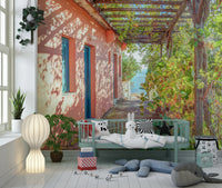 Peach villa exterior wall mural under wooden grapevine trellis, Greek island.