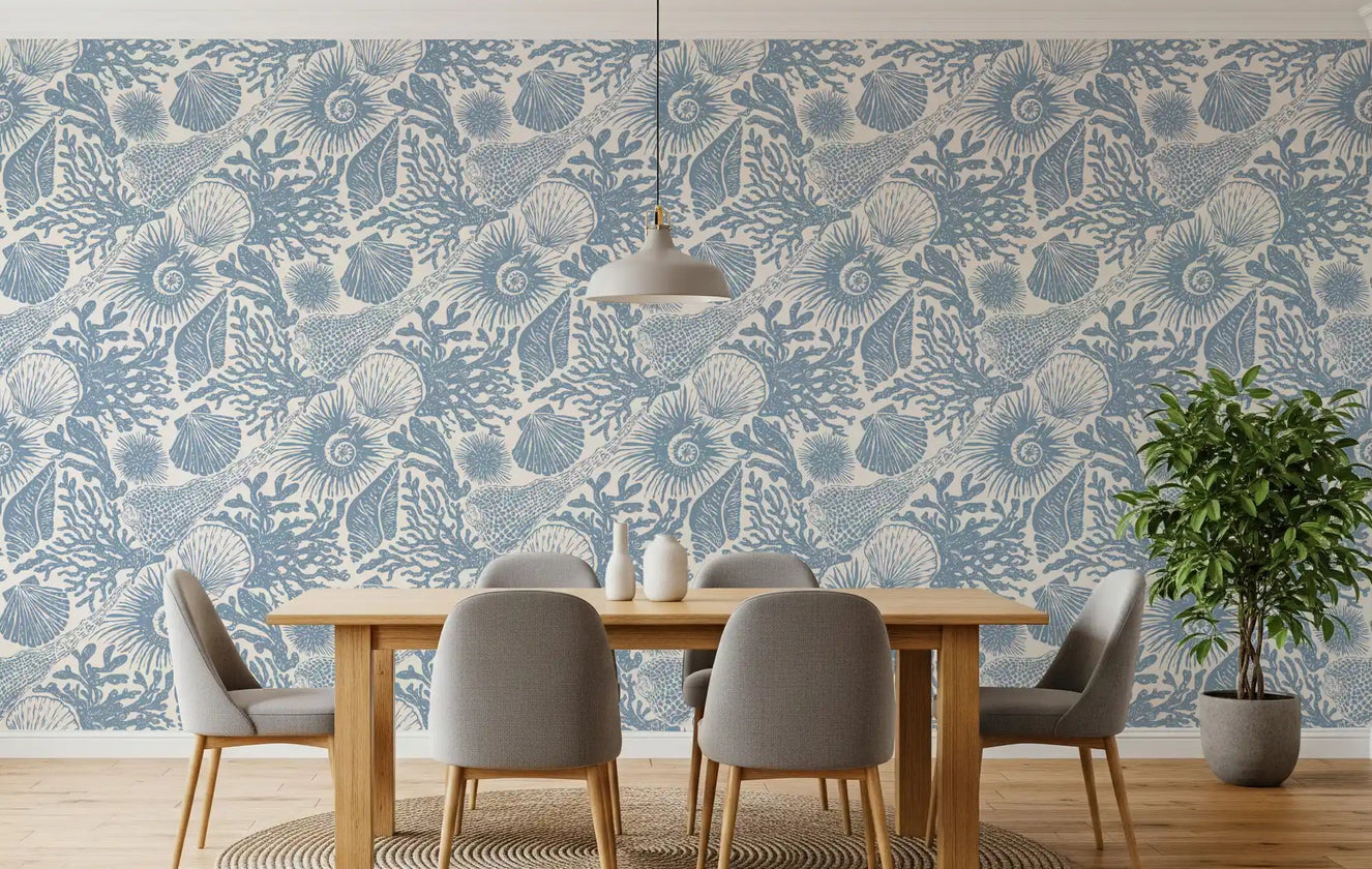 A dining room wrapped in muted blue boho seashell and coral wallpaper