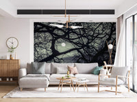 Tangled dark limbs from this Lunar Silhouette wall mural hang above a living room.