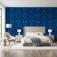 Cobalt folk art wallpaper behind a tufted cream bed with a blush accent chair GD12263