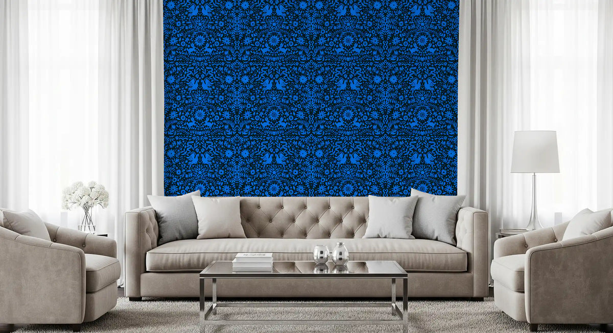 Cobalt folk art wallpaper behind a grey tufted sofa between tall curtained windows GD12263