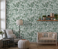 Nursery with wooden crib floor lamp and pouf against green leaf canopy wallpaper GD12325