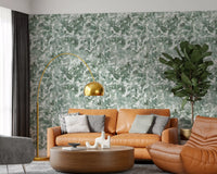 Tan leather sofa and brass arc lamp beside misty forest leaf canopy wallpaper GD12325