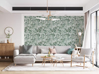 Grey sofa and wood sideboard under gold chandelier against green leaf canopy wallpaper GD12325