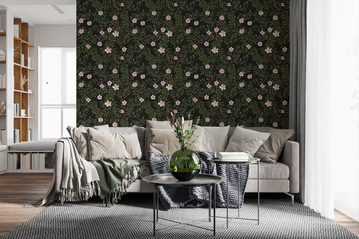 Soft pink floral vines charcoal wallpaper behind a grey sofa with knit throw and round side tables GD12467
