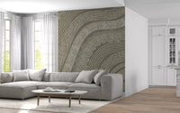 Taupe wavy etched lines mural behind a grey sectional sofa by a bright bay window GD12471