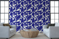 Cobalt geometric shapes wallpaper behind two pale blue armchairs and a round wood table GD12480