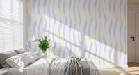 Blue wave wallpaper in a sunlit bedroom with a white bed and floor lamp GD12498