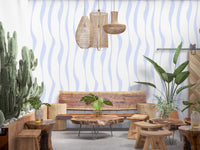 Flowing blue hues wallpaper in a boho lounge with a wood bench and cacti GD12498