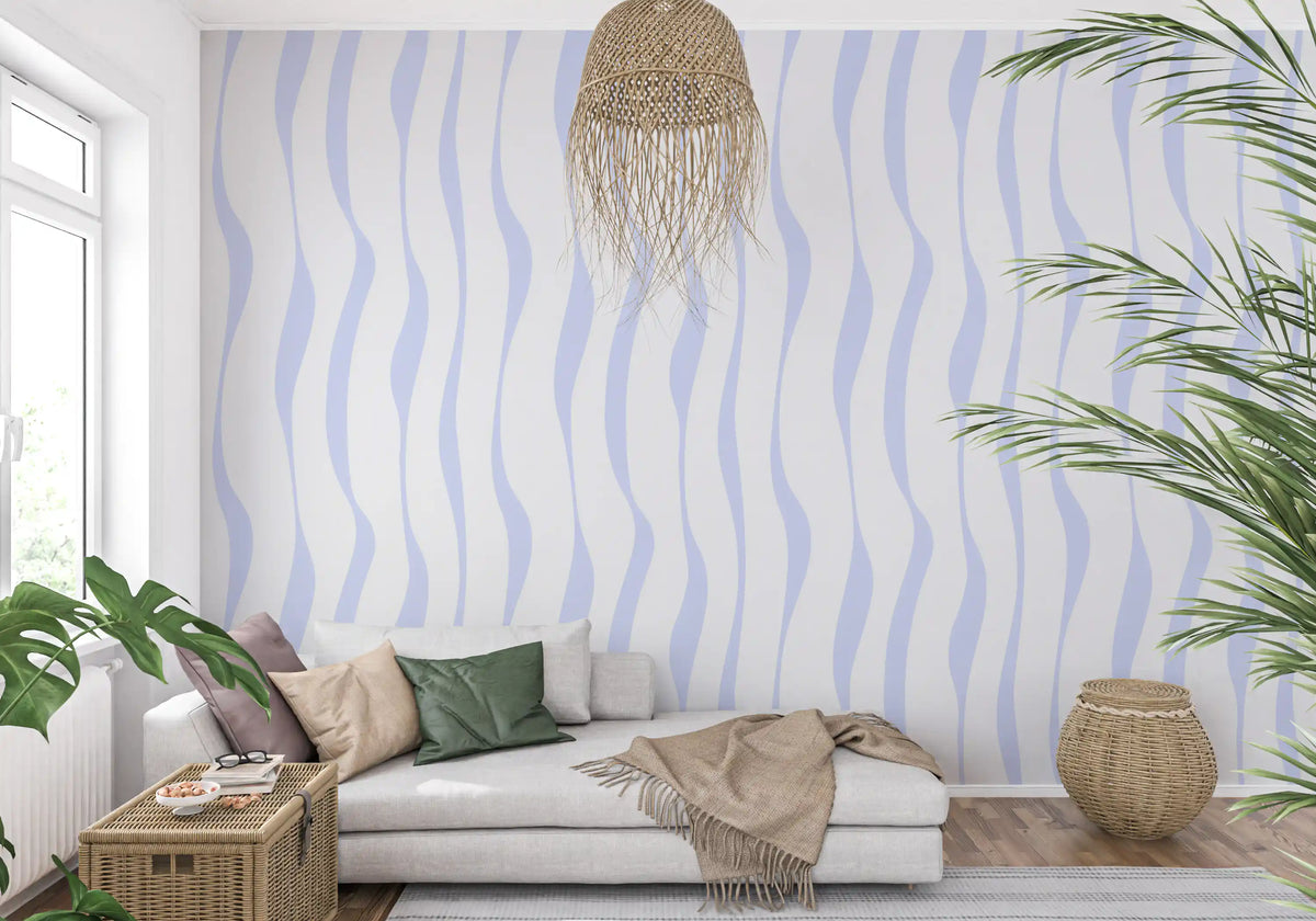 Blue wave wallpaper behind a beige sofa with a macrame hanging and palm GD12498
