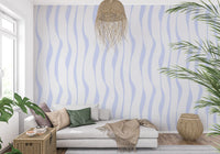 Blue wave wallpaper behind a beige sofa with a macrame hanging and palm GD12498