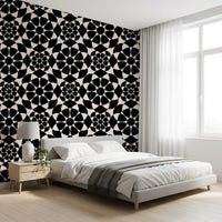 Geometric circle wallpaper behind a white bed with a wooden nightstand and grey throw GD12506