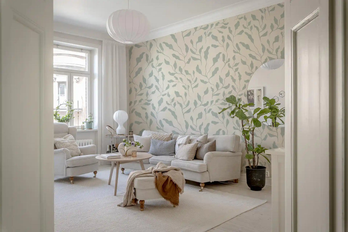 Cream and sage leaf wallpaper in a bright living room with a cream sofa and paper lantern GD12687