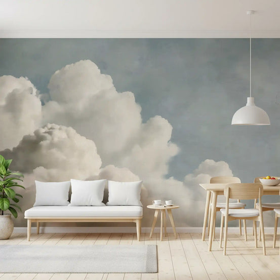 Dreamy painted clouds wall mural in a living nook with white bench sofa and wood chairs GD12775