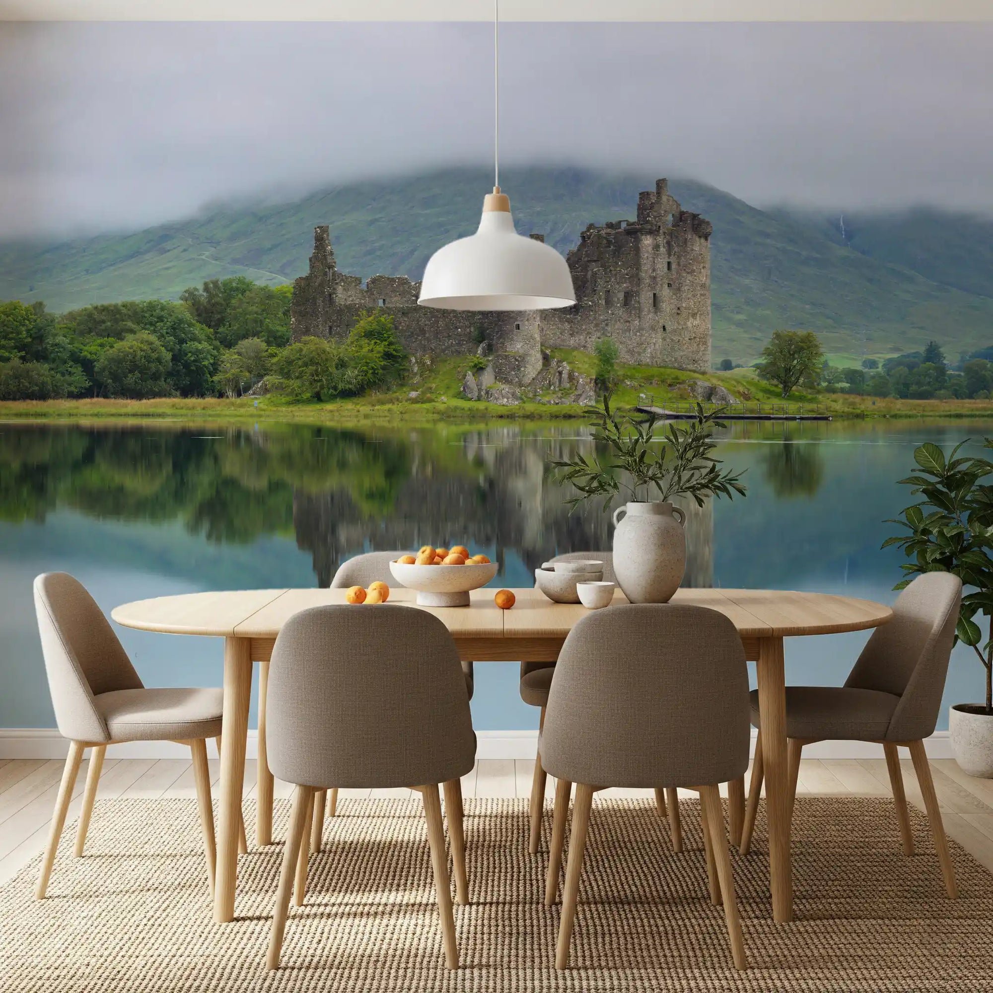 Misty lochside castle ruins wall mural behind a round dining table with grey chairs GD12805