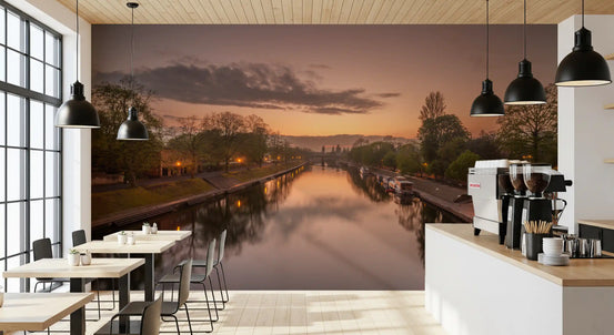 Sunset canal wall mural behind a bright cafe bar with coffee machines and window tables GD12847