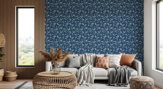 Navy camo abstract wallpaper behind a gray sofa with orange cushions and rattan side table GD13571