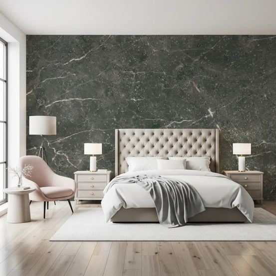 Charcoal marble wallpaper behind a tufted beige bed and pink armchair in a bright bedroom GD14126