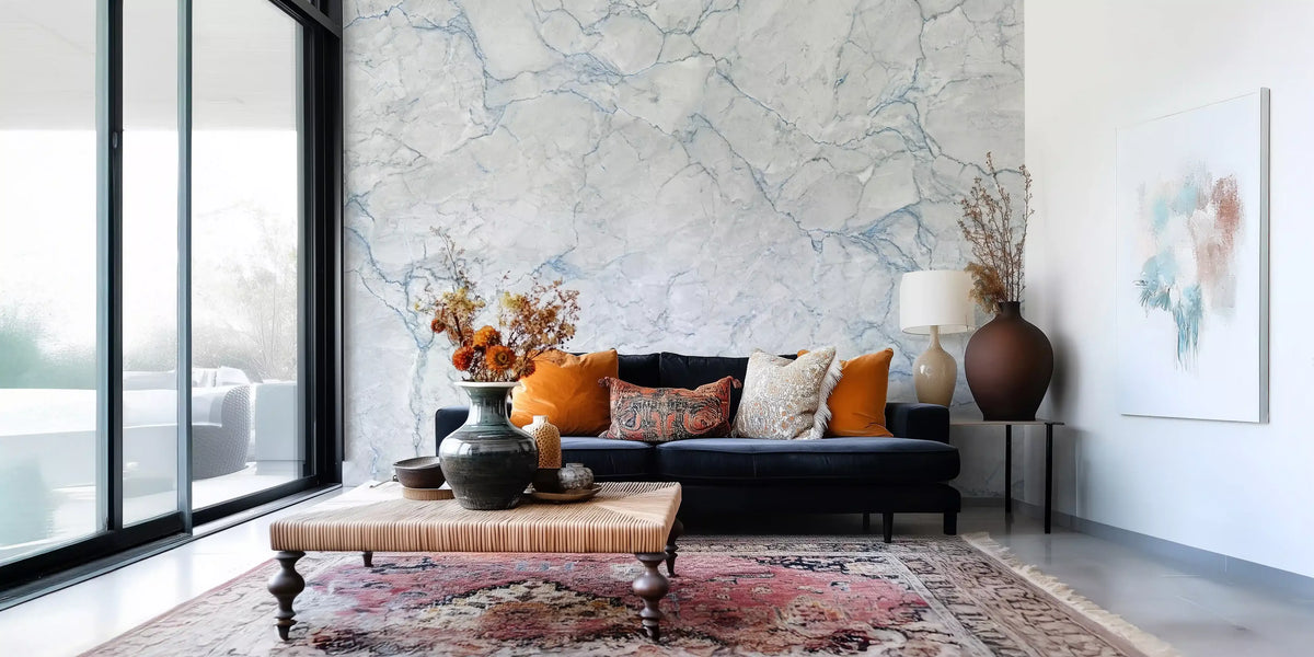 Marble wallpaper mural behind navy sofa with orange cushions, leather ottoman and pink rug GD14156