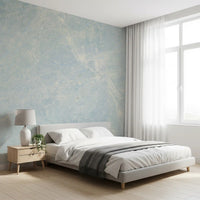 Low white bed with wood nightstand and sheer curtains on a pale blue marble wall GD14187