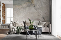 Stone effect mural behind a gray sofa with green throw and round black side tables GD14211