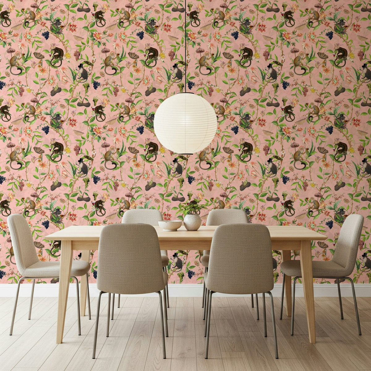 A Primate's Garden Party pink wallpaper behind a light wood dining table with beige chairs