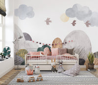 Abstract watercolor landscape wallpaper mural in muted hills and clouds behind a pink toddler daybed in a sunny nursery