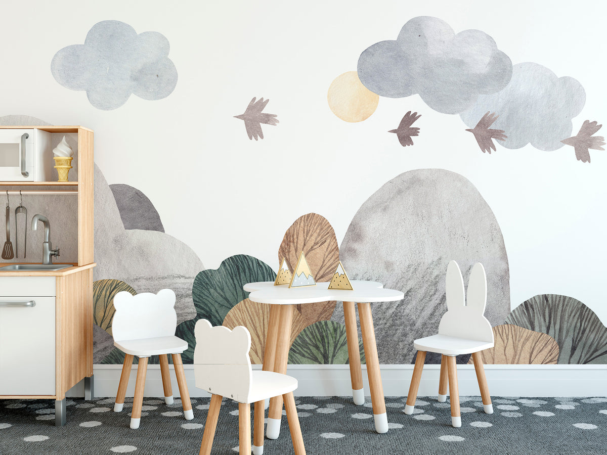 Abstract watercolor landscape wallpaper mural with soft hills, clouds and birds in a kids playroom with toy kitchen and animal chairs
