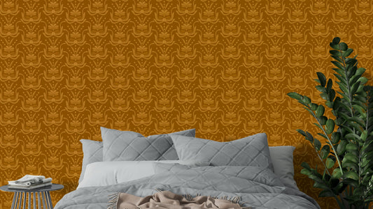 Amber Hues wallpaper in warm mustard tones above a grey quilted bed beside a green ZZ plant in a bedroom