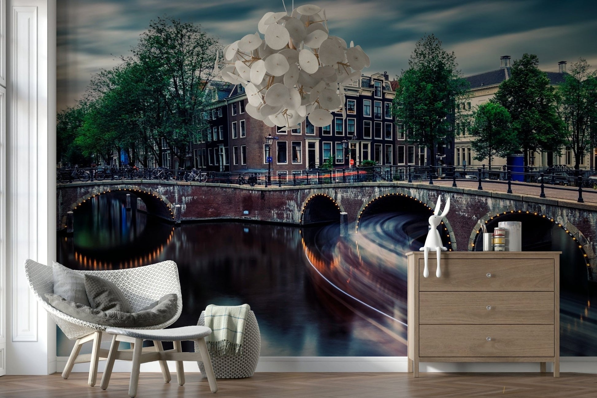 Amsterdam Canal Dreams wallpaper mural of the dusk canal behind a grey wicker armchair and wood dresser in a living room
