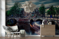 Amsterdam Canal Dreams wallpaper mural of the dusk canal behind a grey wicker armchair and wood dresser in a living room