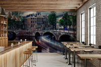 Amsterdam Canal Dreams wallpaper mural of the lit canal bridges behind a wood bar counter and stools in a cafe