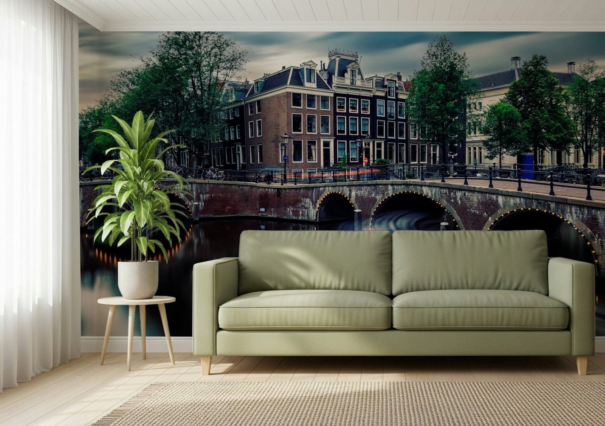 Amsterdam Canal Dreams wallpaper mural of the canal and Dutch houses behind a sage green sofa in a bright living room