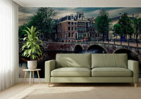 Amsterdam Canal Dreams wallpaper mural of the canal and Dutch houses behind a sage green sofa in a bright living room