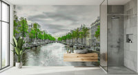 Amsterdam Canal Serenity wallpaper mural of a green-leafed canal beside a tiled walk-in shower and wood vanity in a bathroom