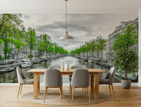 Amsterdam Canal Serenity wallpaper mural of a tree-lined canal and gray townhouses behind a wood dining table and gray chairs