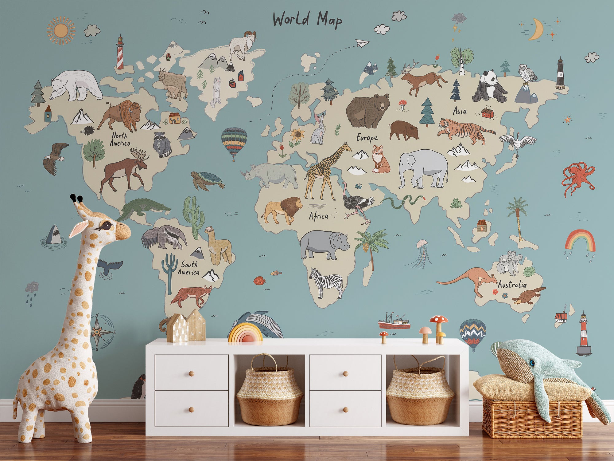 Animal Adventure Atlas wallpaper mural in sage green behind a white console with woven baskets and a plush giraffe in a kids room