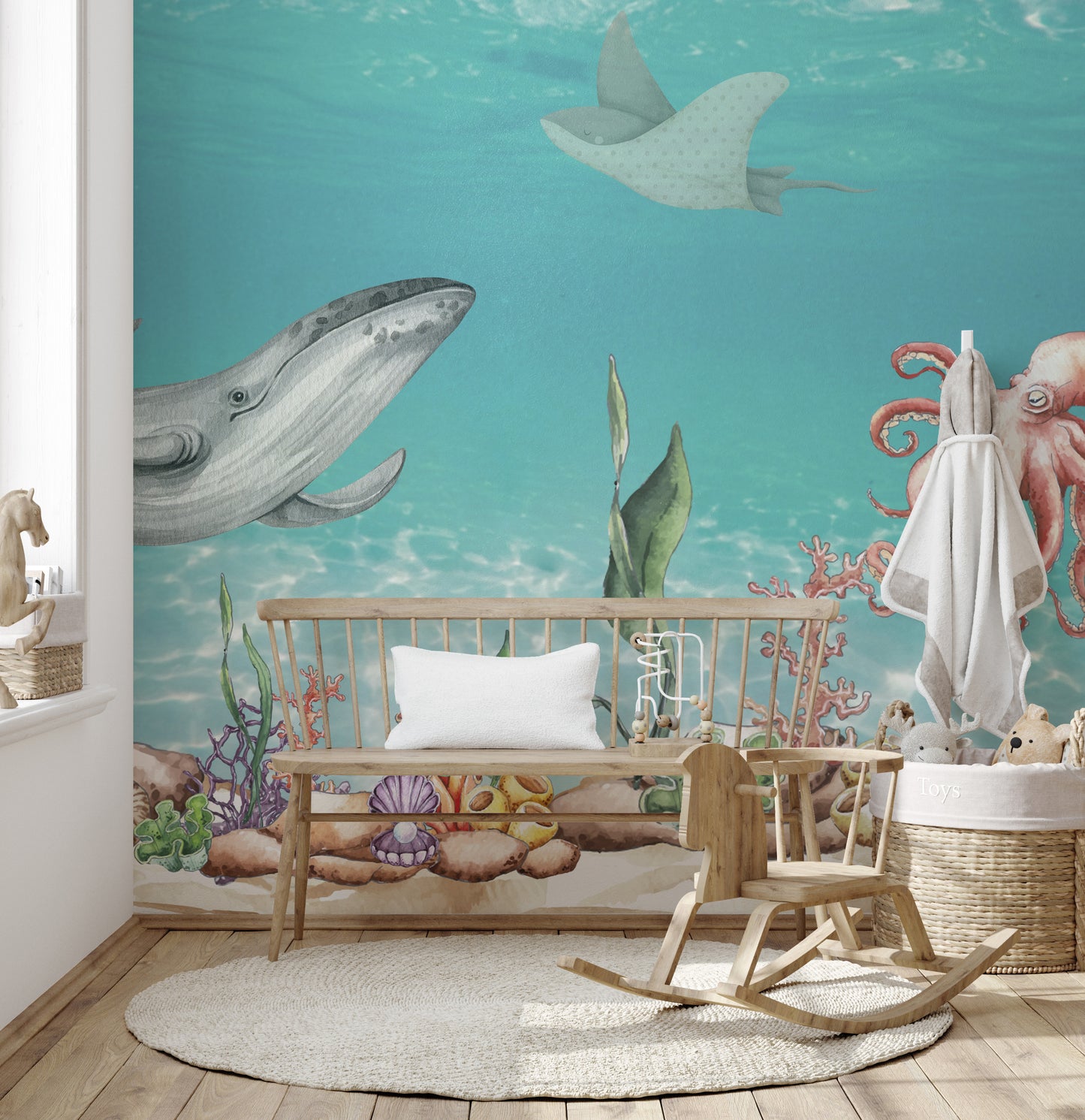 Aquatic Harmony wallpaper mural showing a gray whale and octopus over coral behind a wood crib bench in a nursery