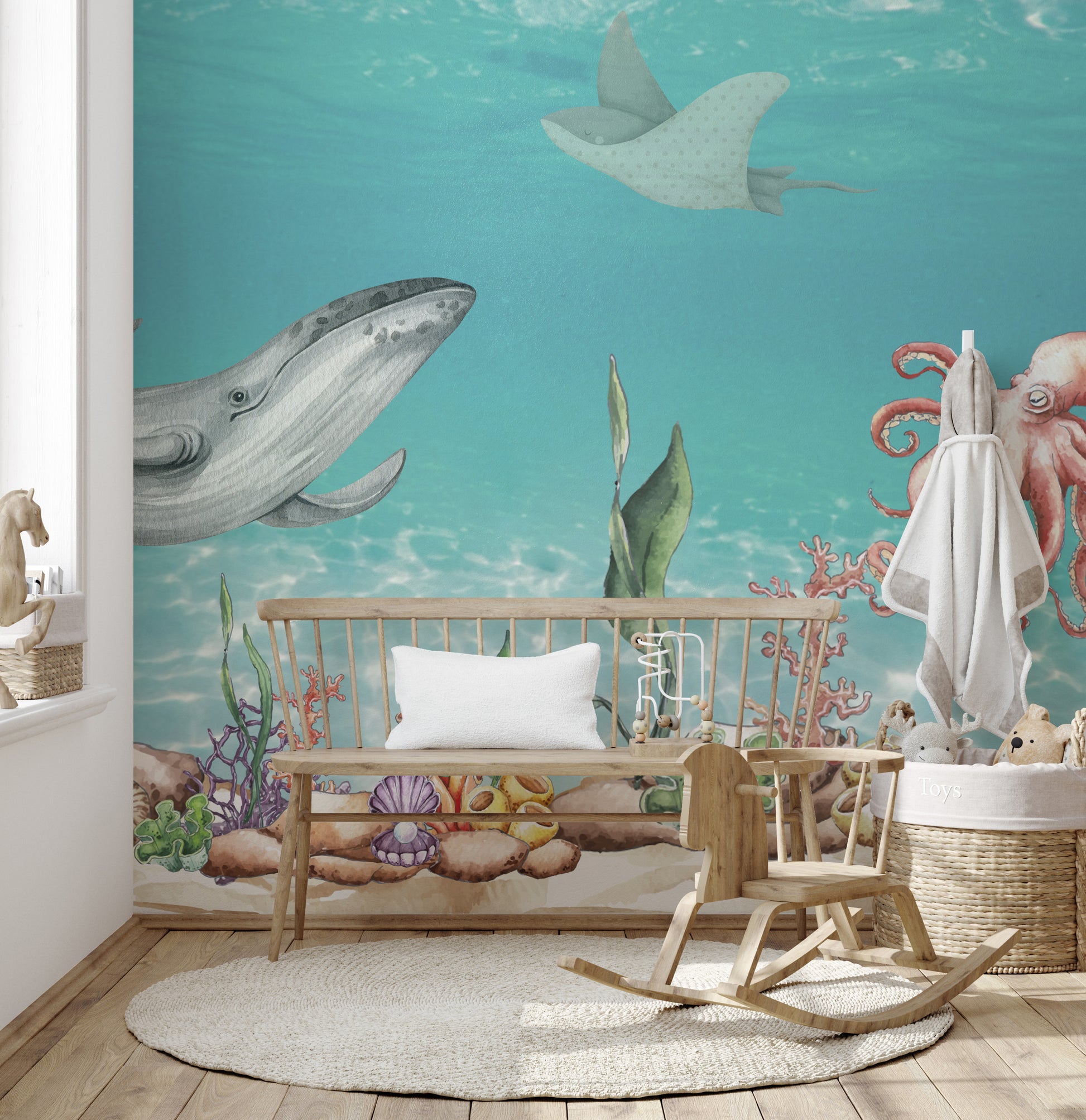 Aquatic Harmony wallpaper mural showing a gray whale and octopus over coral behind a wood crib bench in a nursery