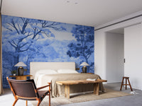 Watercolor Autumn Forest wallpaper mural in blue behind a beige upholstered bed with twin lamps and a wood bench