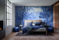 Watercolor Autumn Forest wallpaper mural in deep blue behind a bed with navy bedding beside an exposed brick wall
