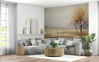 Autumn Vista wallpaper mural in warm gold tones behind a grey sectional sofa and round wood table in a living room