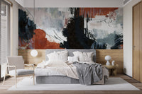 Brushstroke Art wallpaper mural with rust and navy strokes above a grey upholstered bed and rattan armchair in a bedroom