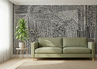 Black And White Maze wallpaper mural behind a sage green sofa and potted plant in a living room